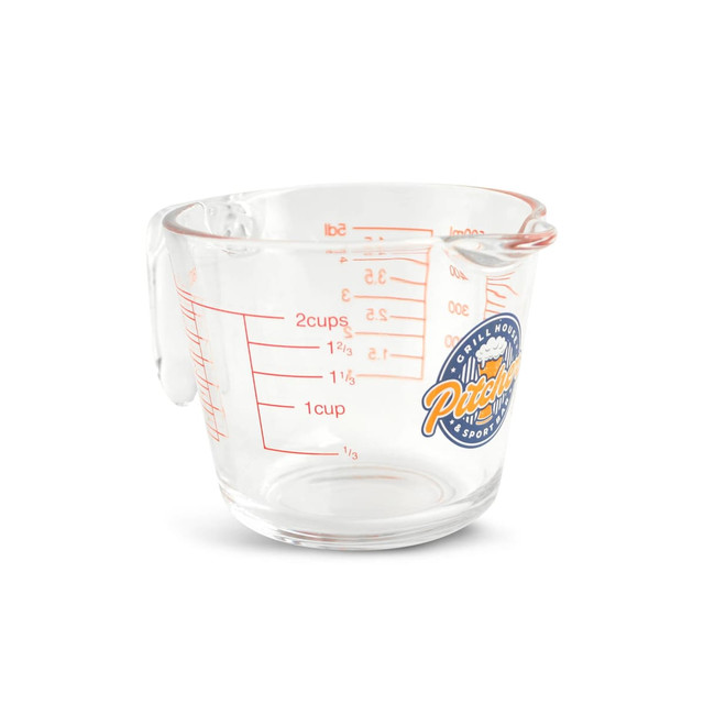 A clear glass measuring jug with red markings and a handle, featuring a logo on the side.