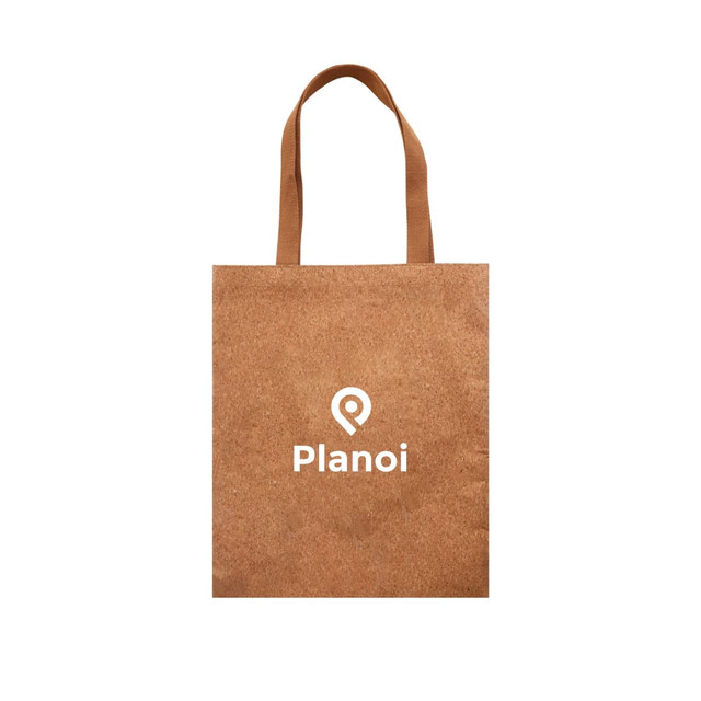 A cork tote bag in a natural brown colour with light brown handles and a logo on the front.