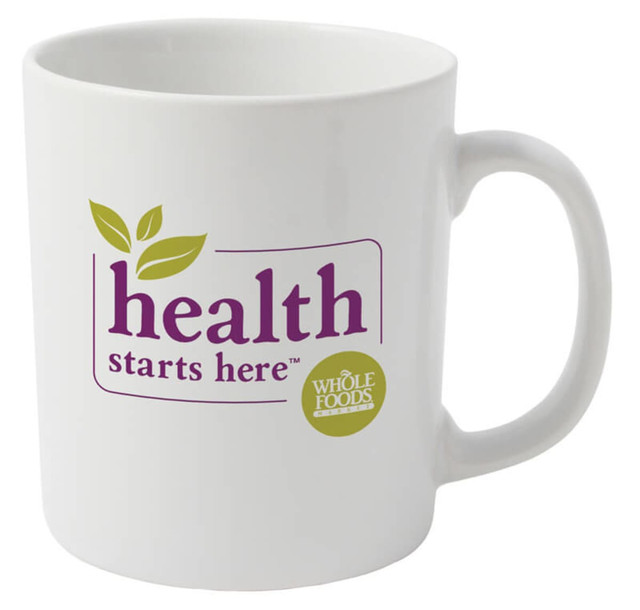 A plain white ceramic mug with a logo and text featuring green leaves and purple lettering.