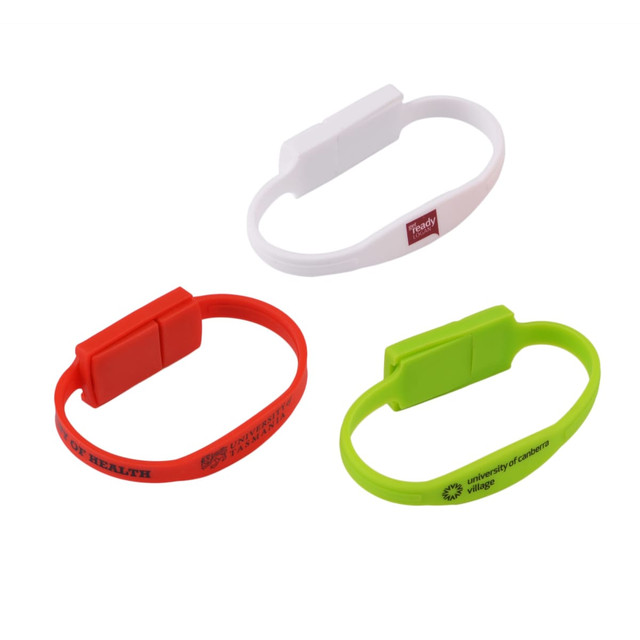 A collection of slim silicone wristband flash drives in red, white, and green, featuring various logos.