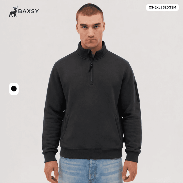 A 1/4 zip fleece in dark grey, featuring a logo on the sleeve. Model displays the product against a neutral background.
