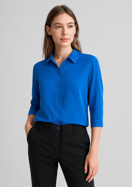 A blue 3/4 sleeve blouse worn by a model, styled with black trousers and featuring a collar and buttons.