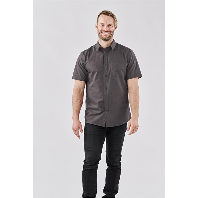 A short-sleeved button-up shirt in dark grey with a subtle pattern, featuring a single pocket and a logo.