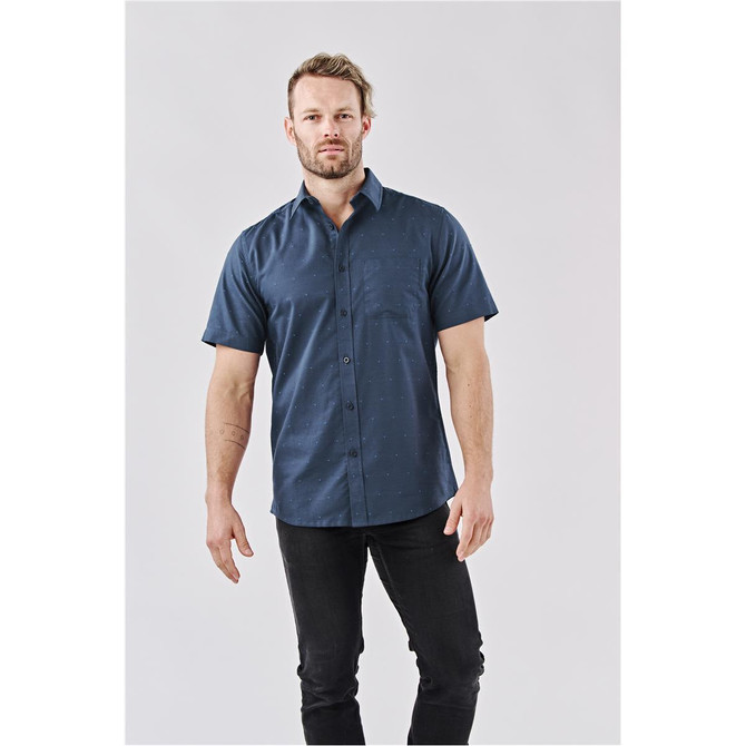 A man wearing a navy short-sleeve button-up shirt with a pocket, featuring a subtle pattern.