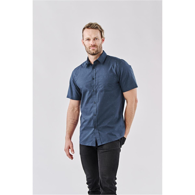 A short-sleeved button-up shirt in navy blue with a subtle pattern and a logo on the chest.