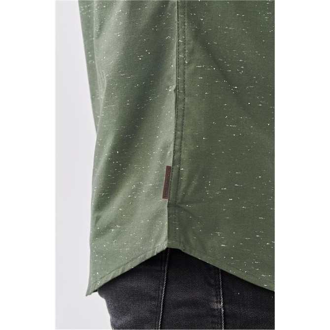 A close-up of a green button-up shirt with a textured finish, featuring a logo at the hem.