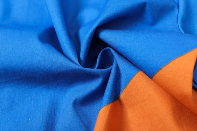 A close-up of fabric featuring vibrant blue and orange tones, showcasing a smooth, soft texture.