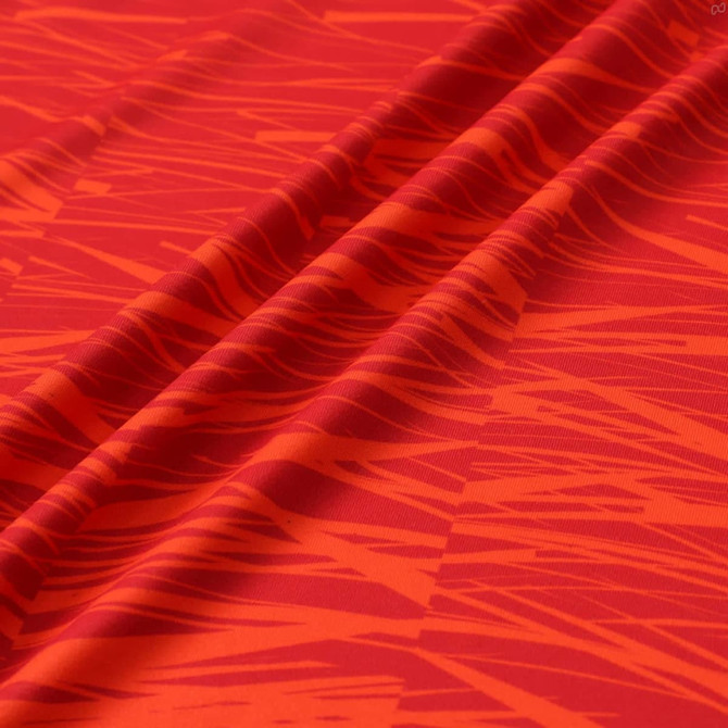 A red hooded sports jumper featuring a bold, textured pattern with shades of orange and darker red. The fabric includes a logo.