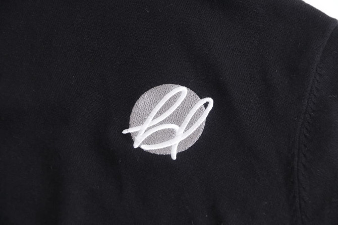 A black turtleneck sweater made from 100% cotton, featuring a simple logo on the fabric.