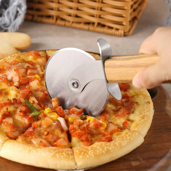 A pizza cutter wheel with a stainless steel blade and a hand-carved wooden handle, slicing through a pizza.