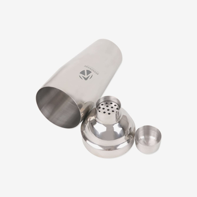 A stainless steel cocktail shaker set with a large shaker, strainer, and jigger, featuring a logo on the shaker.