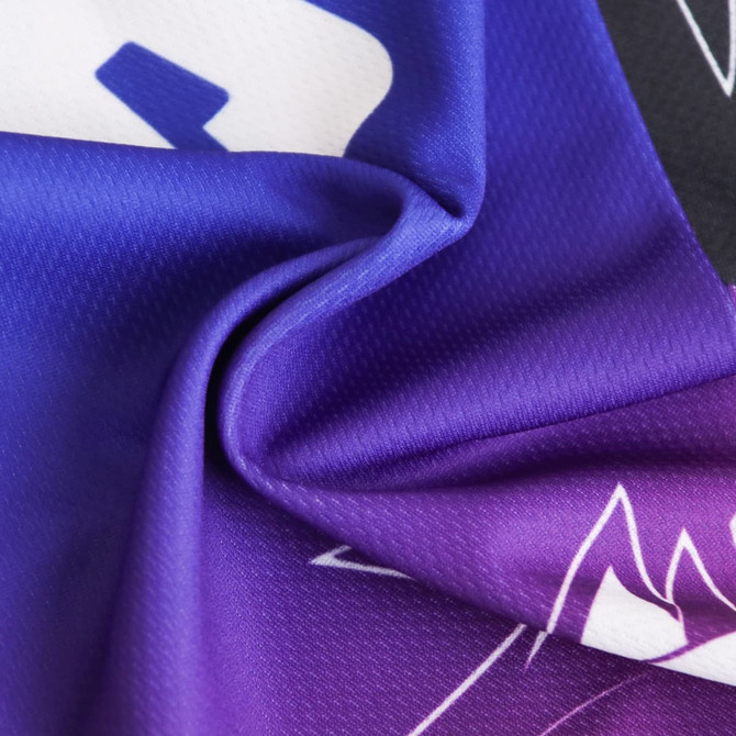 A vibrant scarf featuring a mix of purple and blue patterns, showcasing a smooth, textured fabric. It has a logo.