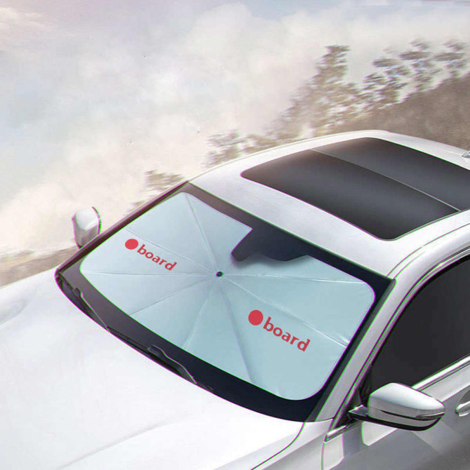 A white car shade umbrella with a logo, positioned on the windshield of a car in an outdoor setting.