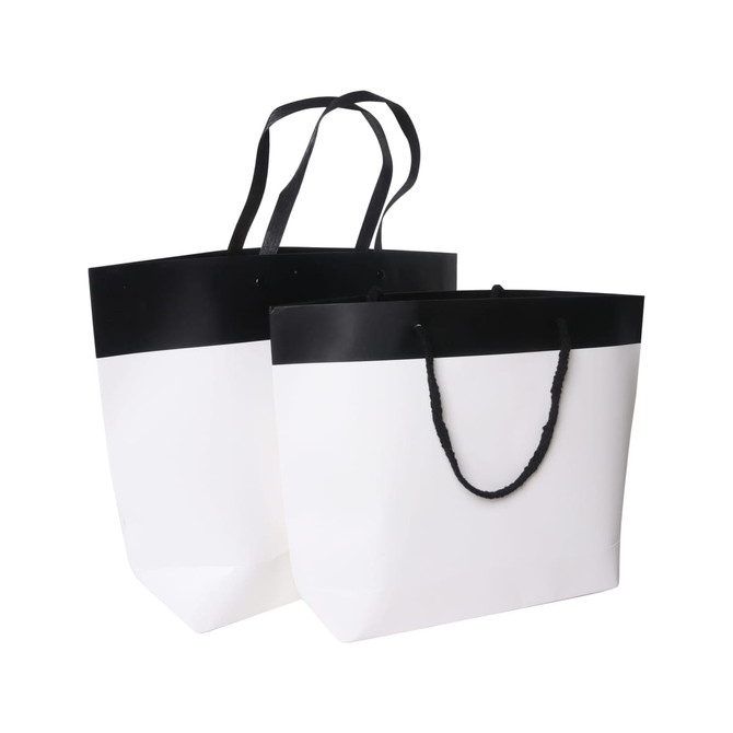 Two small black and white boutique paper bags, featuring a black top section and white lower section with handles.