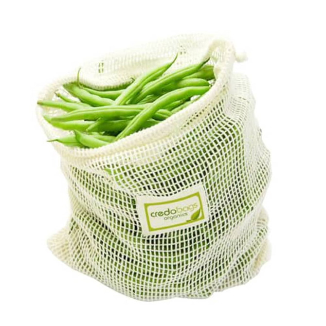 A white organic cotton mesh bag filled with fresh green beans, featuring a logo on the side.
