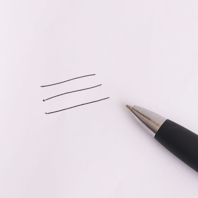 A black stylus pen rests beside three straight lines drawn on white paper. The pen has a sleek design and shiny tip.