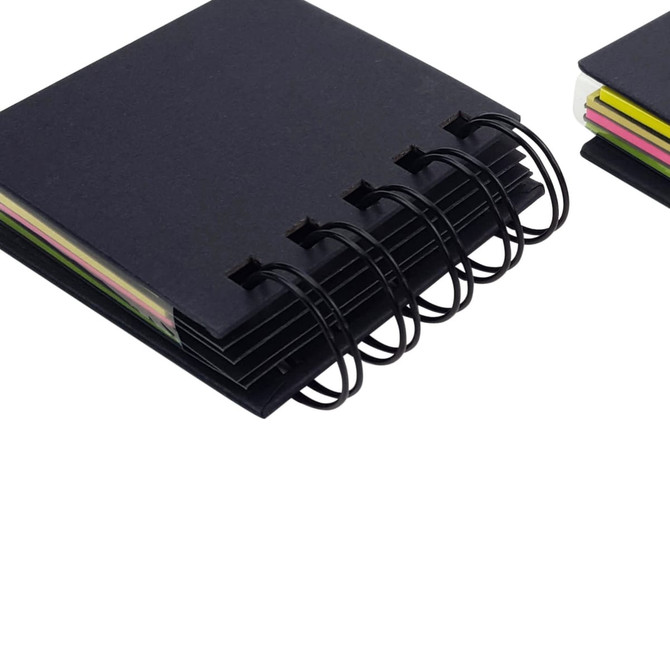 A black, 4-layer recycled sticky notepad with colourful notes visible. It has a binding with rings and additional notepad on the side.