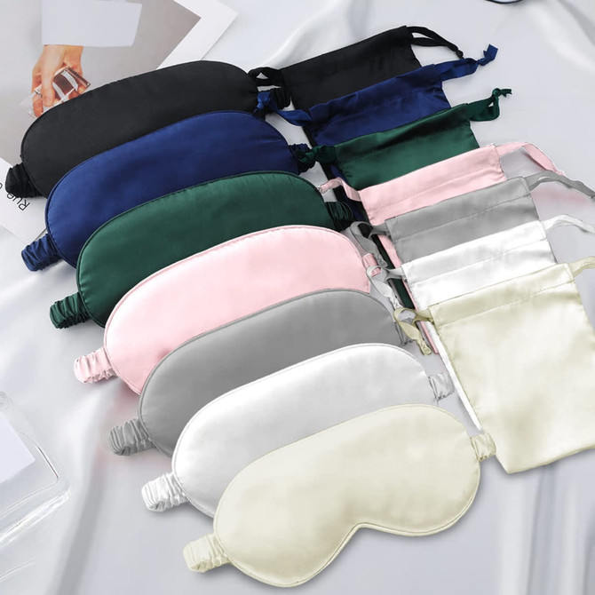 A collection of satin sleep masks in various colours, including black, green, pink, grey, and white, arranged neatly.