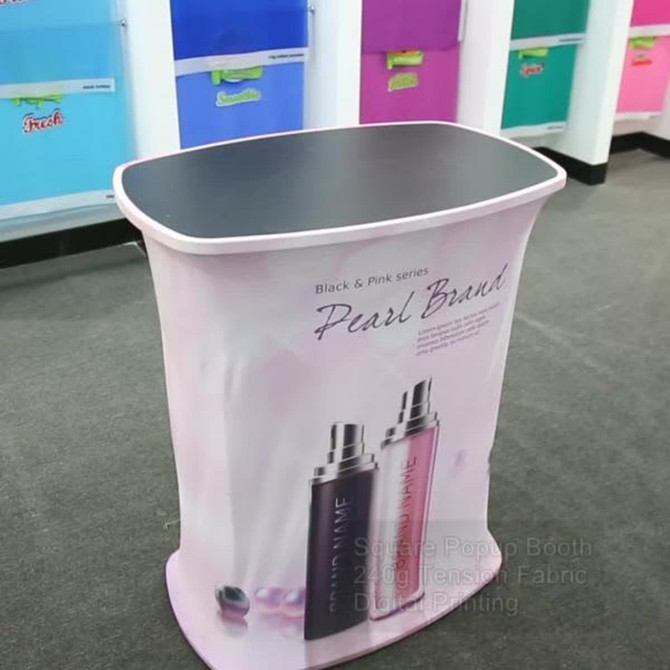 A pink and black promotional display booth with a curved design and a black top surface. It features branding elements.