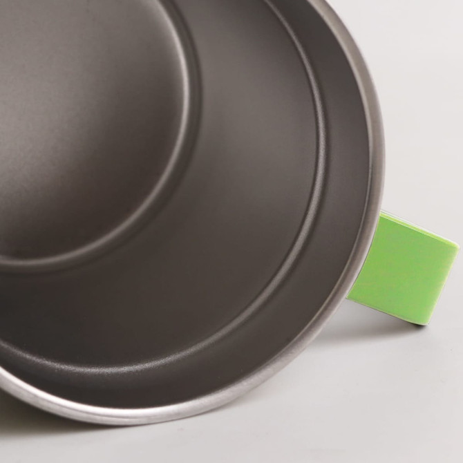 A stainless steel mug with a green handle, featuring a smooth metallic interior and a modern design.