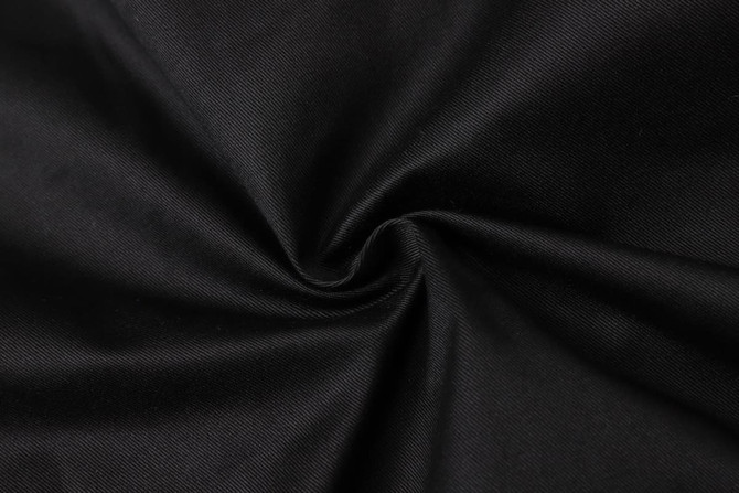 A close-up of black fabric with a textured surface, showcasing its smooth, twisted appearance.