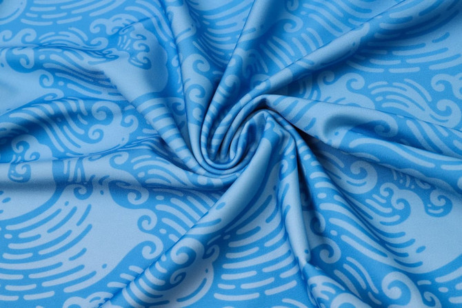 A blue fabric with a swirling wave pattern, suitable for rashies or swimwear, featuring a smooth texture.