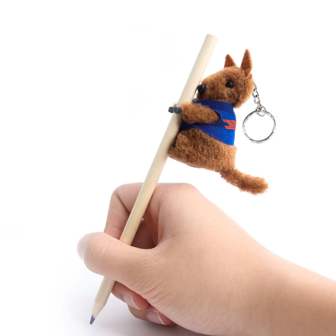A brown kangaroo plush toy is clinging to a pen, featuring a small keychain attachment.