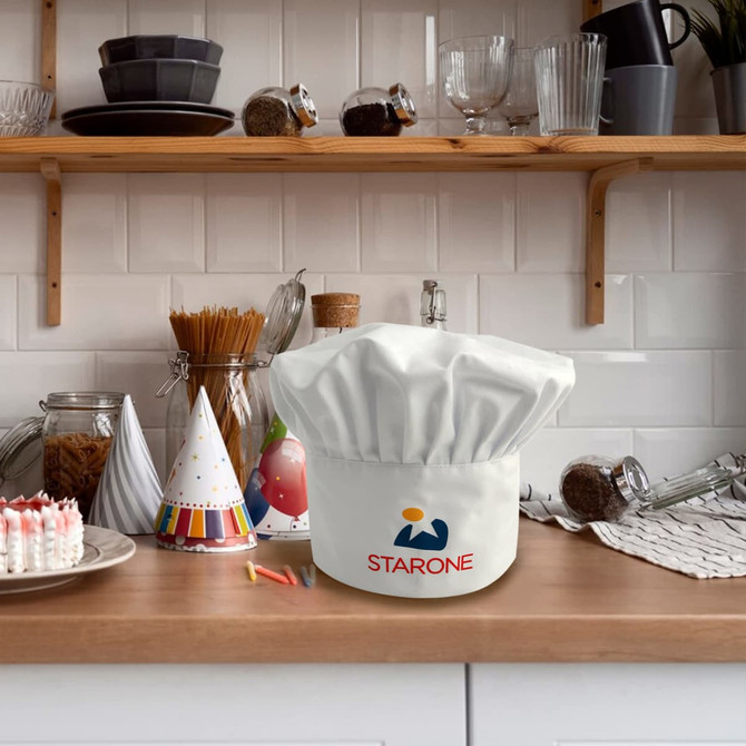 A white chef hat with a logo on a kitchen countertop, surrounded by kitchenware and decorations.