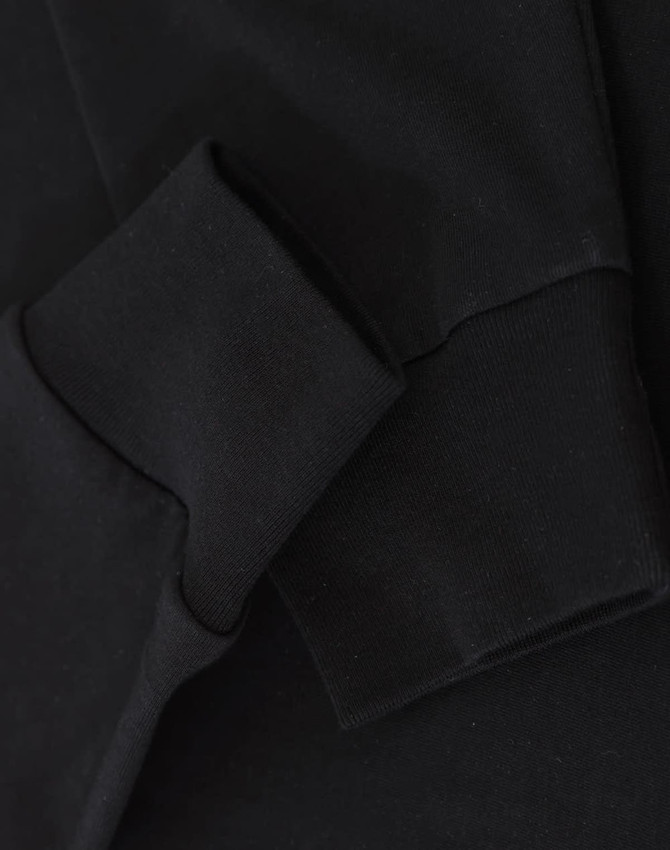 A black long-sleeve tee shirt with a close-up of the sleeve and cuff detailing. It features a logo.