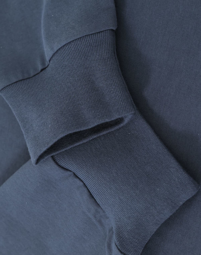 A close-up of navy blue cotton tee shirt cuffs with ribbed detailing, featuring a logo on the fabric.