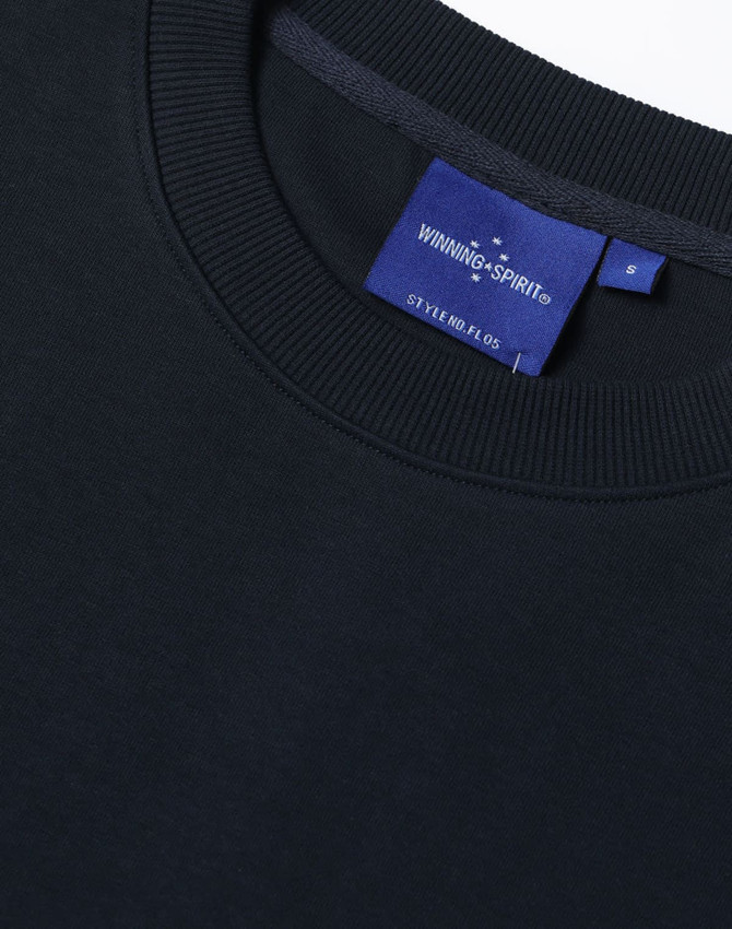 A dark navy unisex crew neck sweater with ribbed detailing and a branded label inside the collar.
