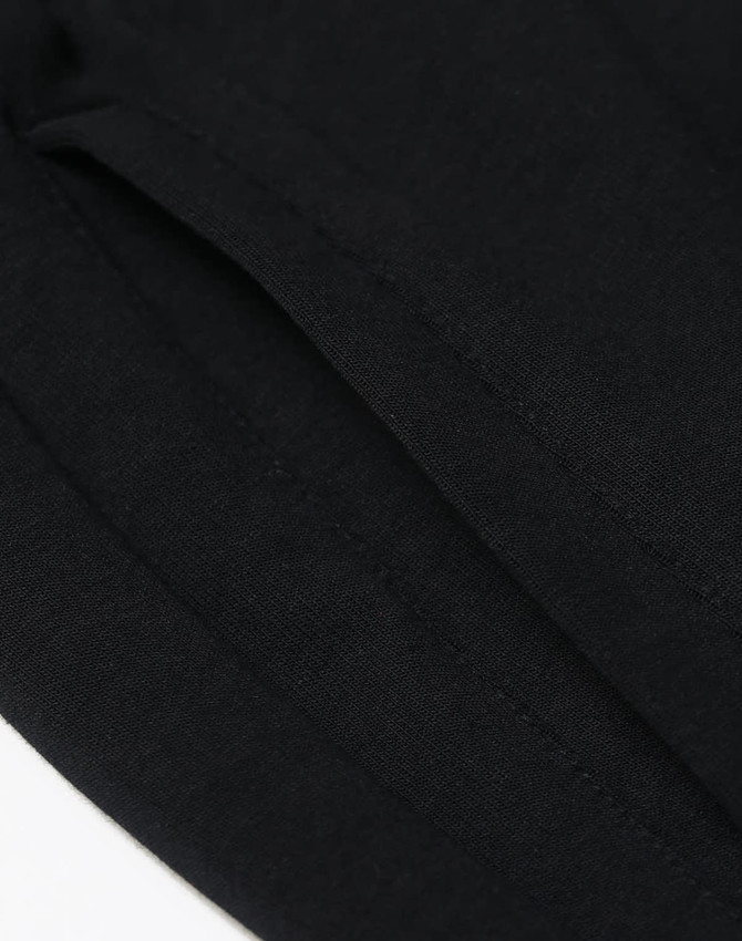 A close-up of black unisex Airlayered CVC sweatpants, featuring smooth fabric with visible seams and a branding logo.