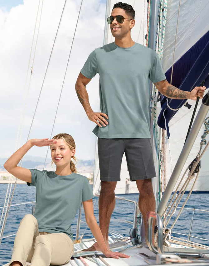 A pair of people wearing a light blue tee shirt on a sailboat, with a logo visible on the shirts.