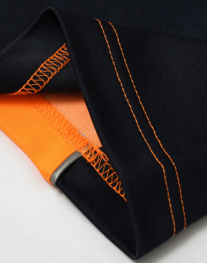 A close-up of a navy polo shirt featuring orange detailing and visible stitching on the collar and hem.