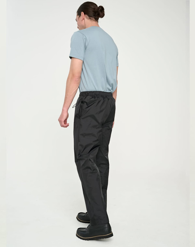 Lightweight nylon waterproof rain pants in black, modelled by a person wearing a blue T-shirt and black shoes.