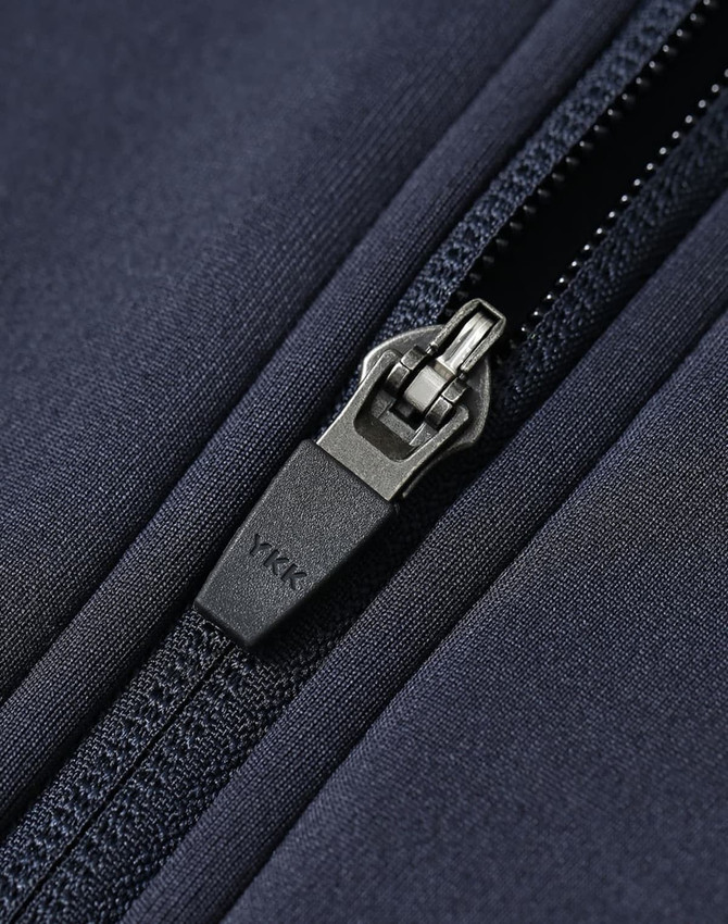 A dark navy sustainable softshell jacket featuring a zippered front with a durable fastening.