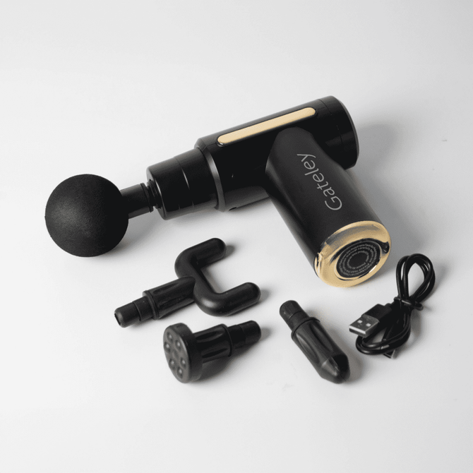 A black and gold massage gun with multiple attachments and a charging cable. It features a logo on the handle.
