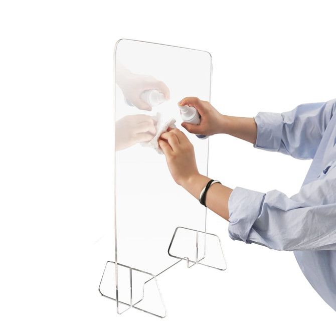 A clear personal protection screen held up with a hand wiping it clean, featuring a simple stand.