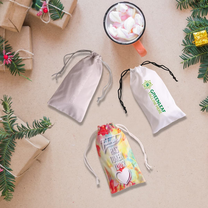 Three drawstring pouches in light grey, white, and a colourful design, placed on a festive background with gifts and greenery.