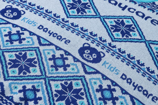 A blue jacquard-patterned sweater featuring bear motifs and snowflake designs, with a logo present.