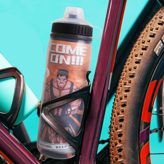A drink bottle with a double wall design, featuring a graphic on its surface, placed in a bike holder. Predominantly orange and black.