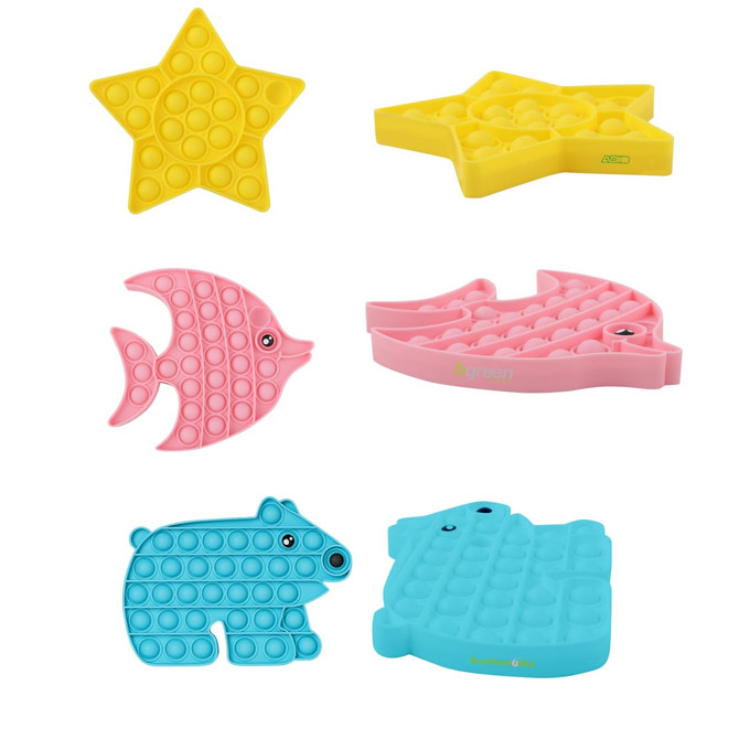 Various fidget toys in bright colours including a yellow star, pink fish, blue bear, and green whale shapes.