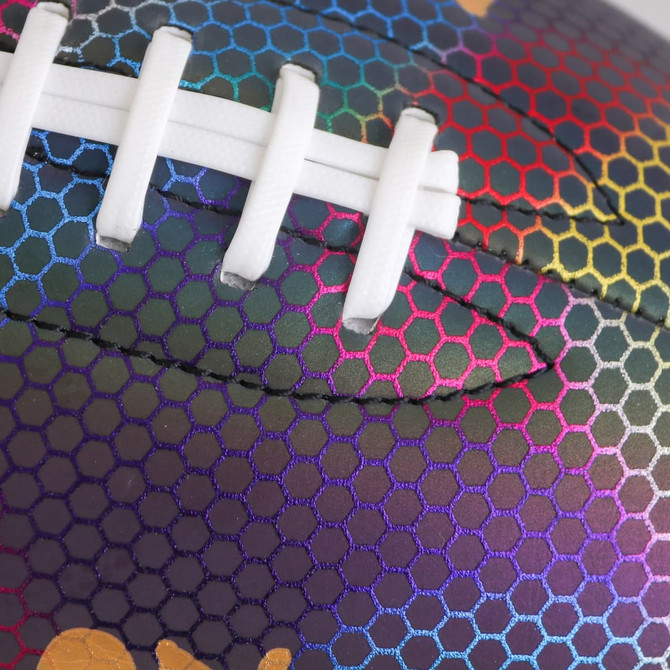 A holographic American football in vibrant rainbow colours with a textured pattern and white laces.