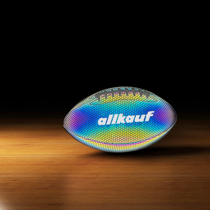 A holographic glowing American football with a reflective surface, featuring a logo, on a wooden surface.