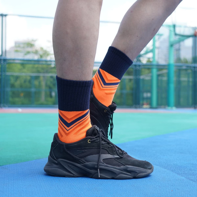 Crew gripper football socks in orange and navy with a towel bottom, worn with black athletic shoes. Crew gripper football socks in orange and navy with a towel bottom, worn with black athletic shoes.