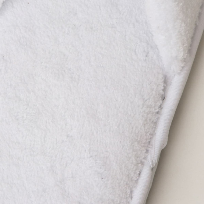 A pair of soft white hotel slippers featuring a plush texture and a branded logo on the side.