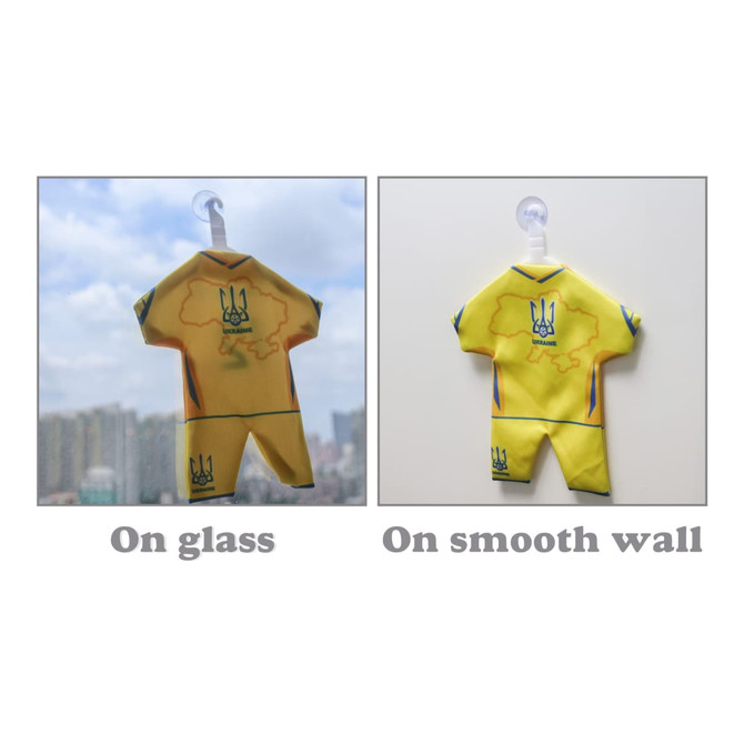 A mini jersey in yellow displayed on glass and a smooth wall, featuring a logo and detailed design.