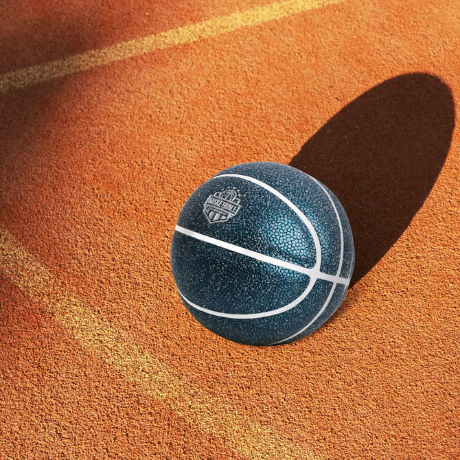 A blue mini basketball with a textured surface and white markings, resting on an orange court.