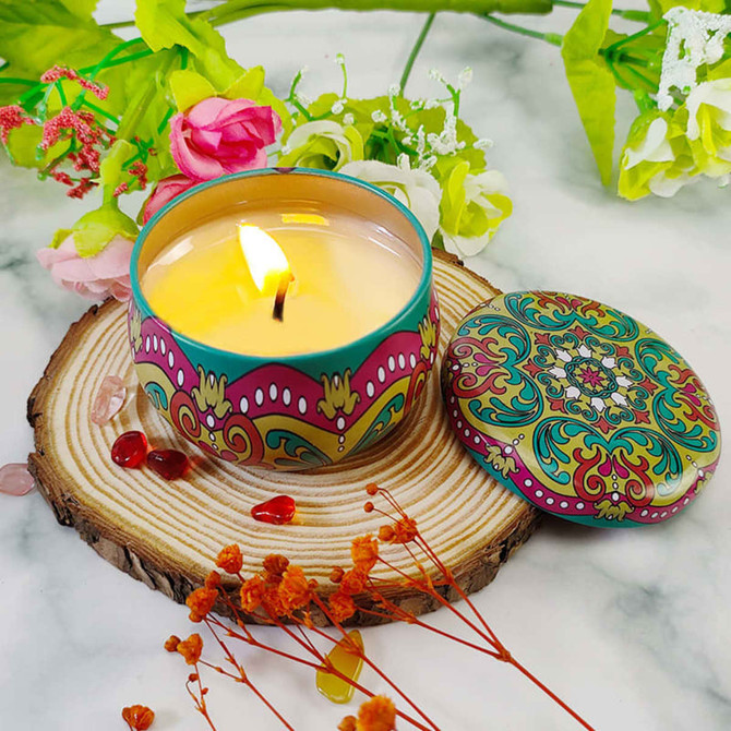 A decorative tin candle with a colourful floral design, surrounded by flowers and natural wood elements. A decorative tin candle with a colourful floral design, surrounded by flowers and natural wood elements.