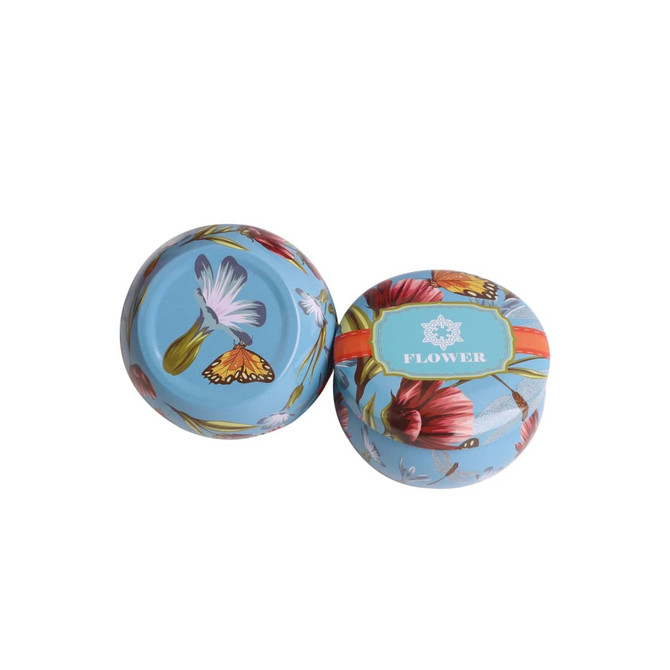 A set of four round tin candles featuring vibrant floral designs and a light blue background.